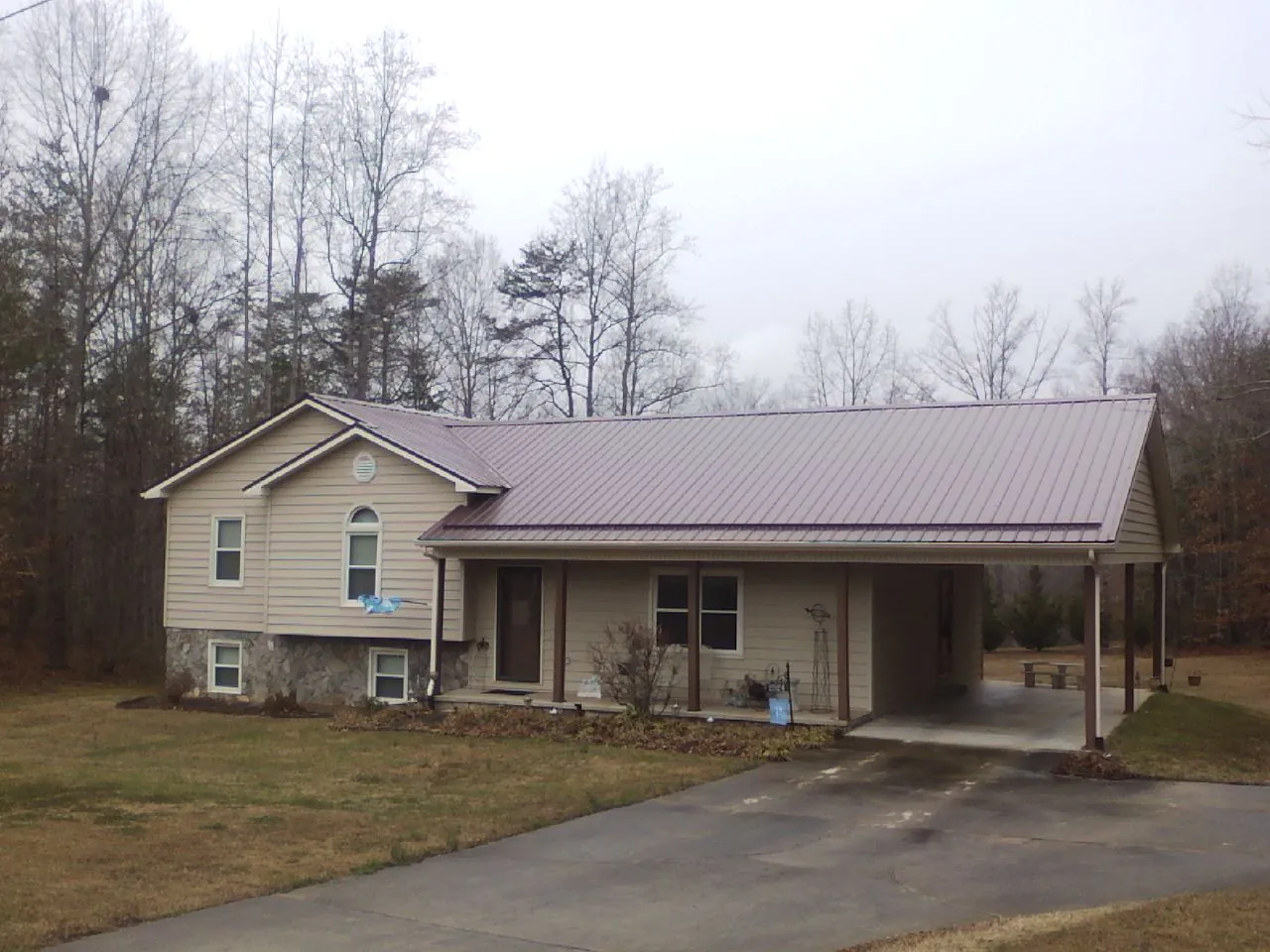 Burgundy metal roof on a tan split level home with an attached carport in Kerby
