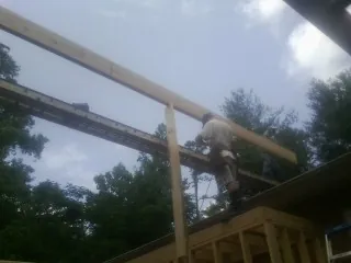 Carpenter setting a ridge beam over a new addition frame — Ice Dam Removal by Roofing Brothers in Kerby