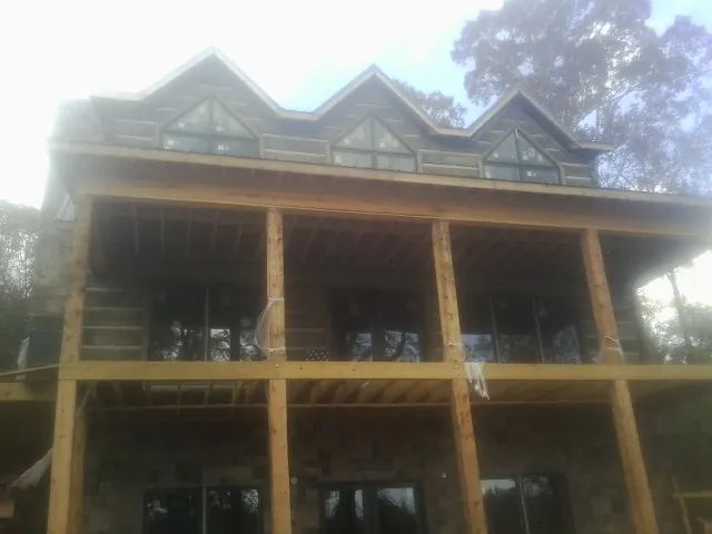 Dormers and porch framing on a large log home under construction — Roof Coating work by our crew in Kerby