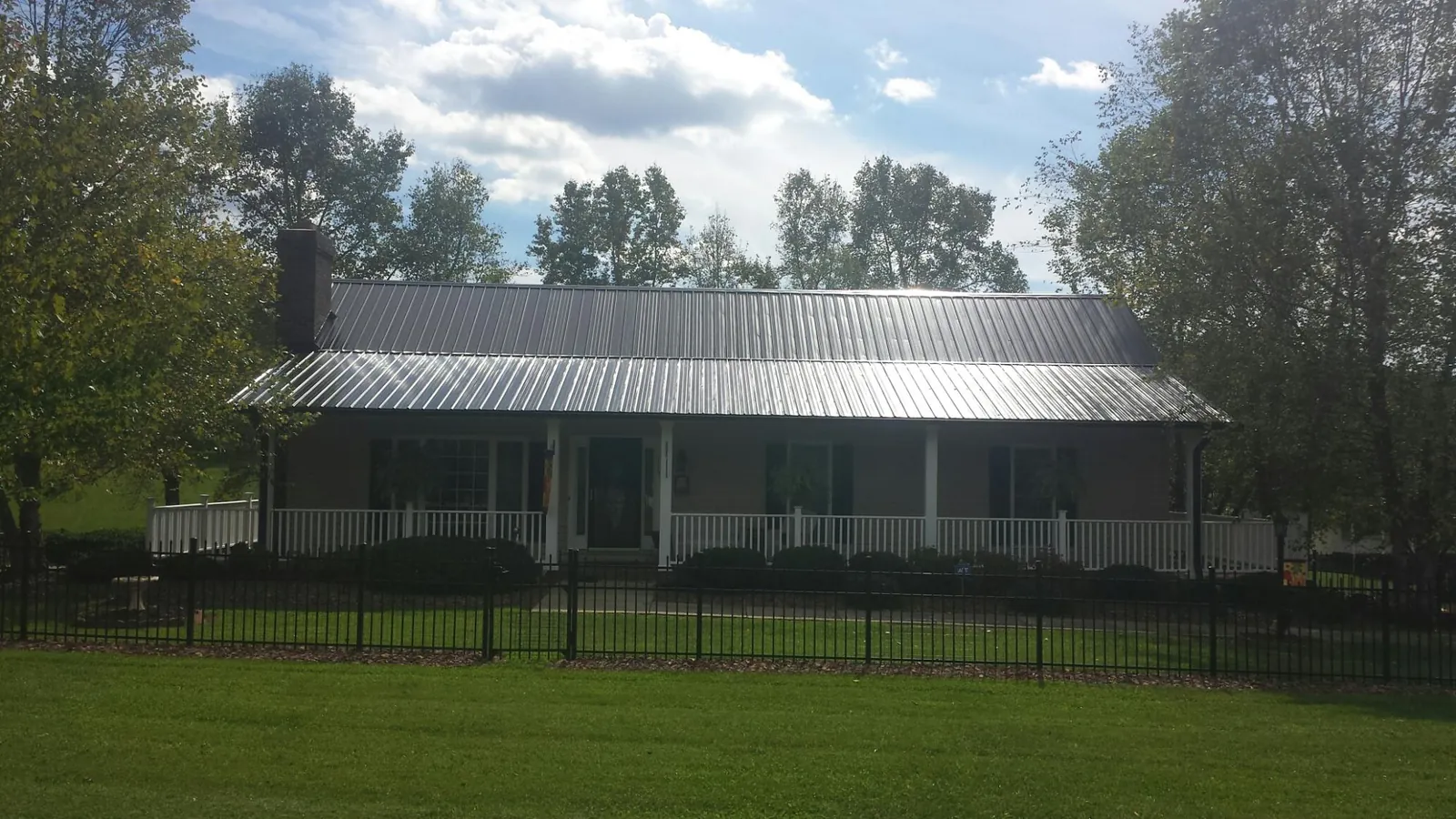 Gray metal roof on a brick ranch with a full width front porch — Gutter Guard Installation work by our crew in Kerby