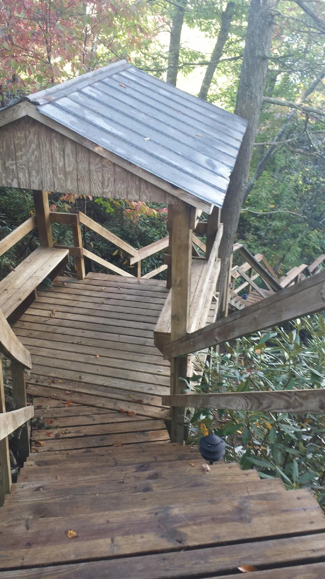 Metal roofed shelter over wooden steps on a wooded walkway — Skylight Repair & Installation work by our crew in Kerby