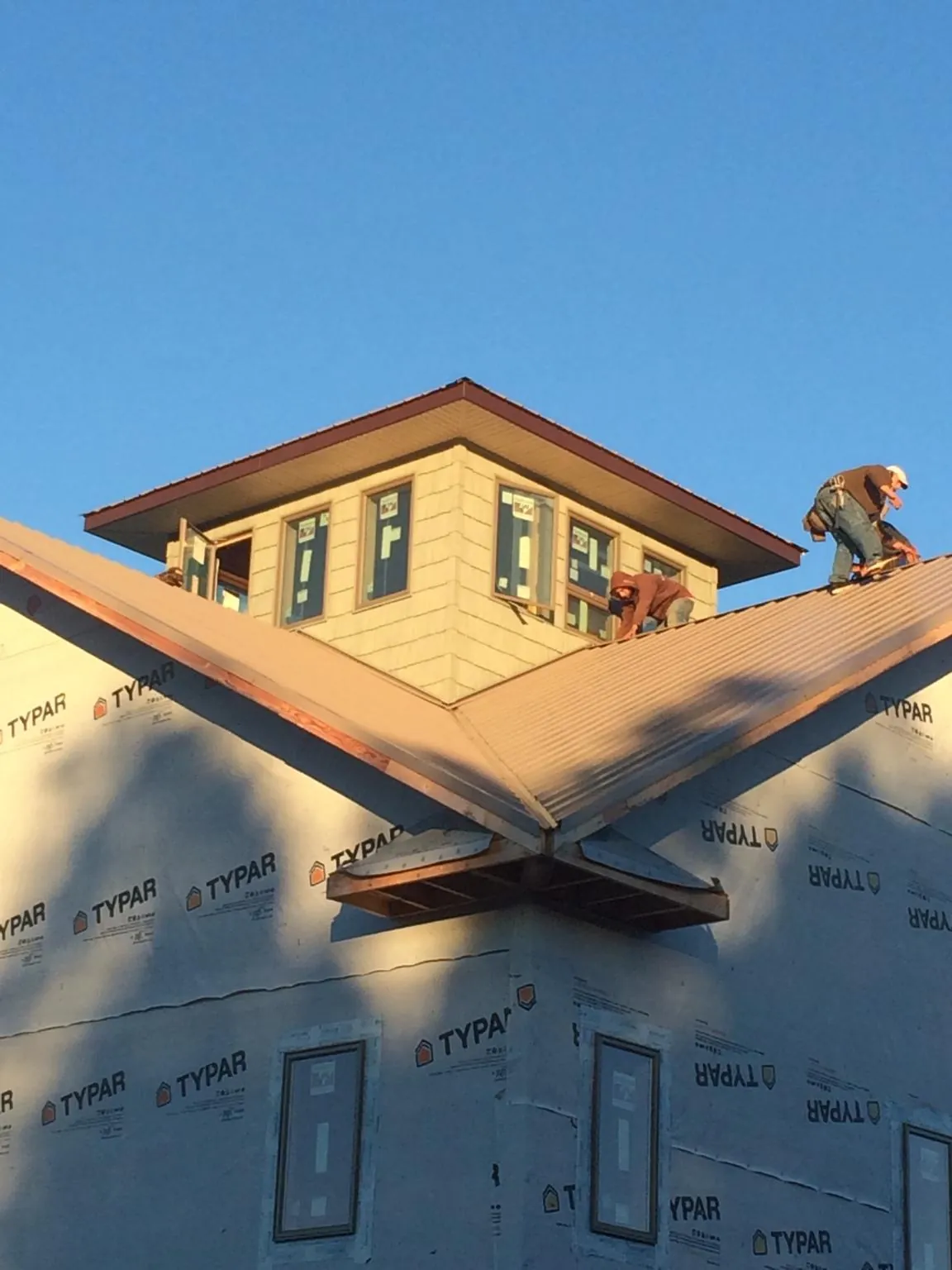 Roofers working around a rooftop cupola on a new metal roof at sunset — Roof Waterproofing in Kerby by Roofing Brothers